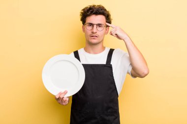 Genç yakışıklı, kafası karışık ve şaşkın hissediyor, sana deli olduğunu gösteriyor. boş tabak kavramı