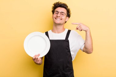 Genç ve yakışıklı adam, kendine güvenerek gülümsüyor. boş tabak kavramı