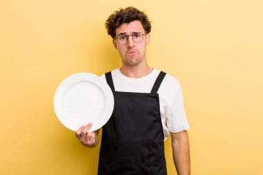 Genç yakışıklı üzgün ve ağlayan mutsuz bakışlı bir adam. boş tabak kavramı