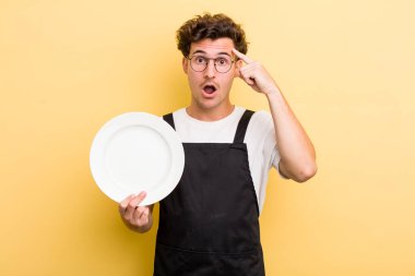 Genç yakışıklı adam şaşırmış görünüyor, yeni bir düşünce, fikir ya da konsept fark ediyor. boş tabak kavramı