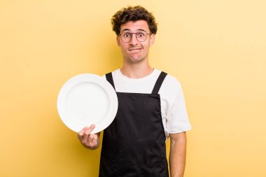 Genç ve yakışıklı adam kafası karışmış ve şaşkın görünüyor. boş tabak kavramı