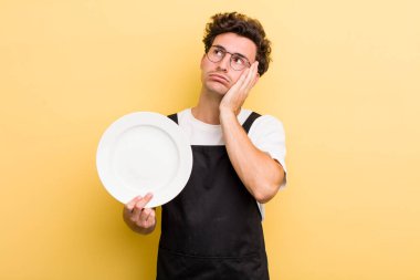 Genç ve yakışıklı bir adam bıkkın, yorgun ve uykulu hissediyor. boş tabak kavramı