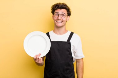 Genç yakışıklı adam mutlu ve hoş bir şekilde şaşırmış görünüyor. boş tabak kavramı