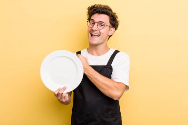 Genç yakışıklı adam kendini mutlu hissediyor ve bir meydan okumayla yüzleşiyor ya da kutluyor. boş tabak kavramı