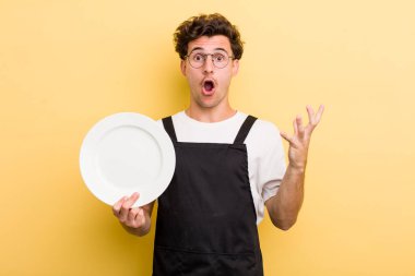 Genç ve yakışıklı adam şok olmuş ve şaşırmış hissediyor. boş tabak kavramı