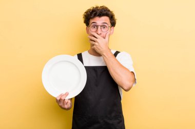 Genç ve yakışıklı adam elleri ile ağzını kapatıyor ve şoka giriyor. boş tabak kavramı