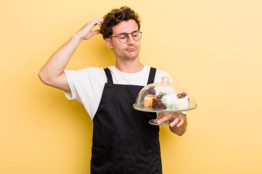 Kafası karışmış, kafası karışmış, kaşınan genç yakışıklı bir adam. Ev yapımı kek konsepti