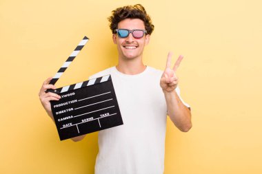 Genç yakışıklı adam gülümsüyor ve mutlu görünüyor, zafer ya da barış işareti yapıyor. film konsepti