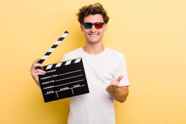 Genç yakışıklı adam mutlu bir şekilde gülümsüyor ve bir konsept sunuyor. film konsepti