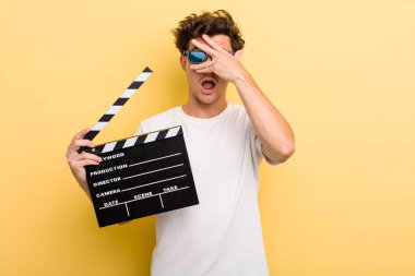 Genç, yakışıklı adam şok olmuş, korkmuş ya da korkmuş görünüyor, yüzünü eliyle kapatıyor. film konsepti