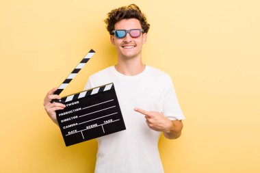 Genç yakışıklı adam neşeyle gülümsüyor, mutlu hissediyor ve bir tarafı işaret ediyor. film konsepti