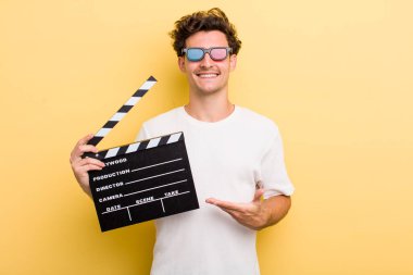 Genç yakışıklı adam neşeyle gülümsüyor, mutlu hissediyor ve bir konsept gösteriyor. film konsepti