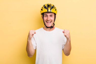 Genç yakışıklı adam şok olmuş hissediyor, gülüyor ve başarıyı kutluyor. Bisiklet konsepti motor konsepti