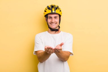 Genç yakışıklı adam mutlu bir şekilde gülümsüyor ve bir konsept sunuyor. Bisiklet konsepti motor konsepti