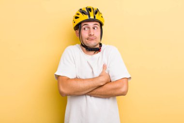 Genç yakışıklı adam omuz silkiyor, kafası karışık ve kararsız hissediyor. Bisiklet konsepti motor konsepti