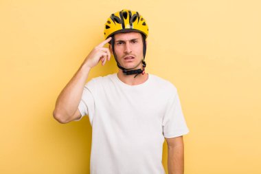 Genç yakışıklı, kafası karışık ve şaşkın hissediyor, sana deli olduğunu gösteriyor. Bisiklet konsepti motor konsepti