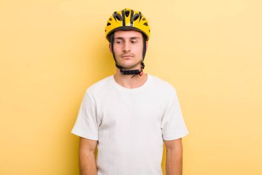 Genç yakışıklı adam üzgün, üzgün ya da kızgın hissediyor ve yana bakıyor. Bisiklet konsepti motor konsepti