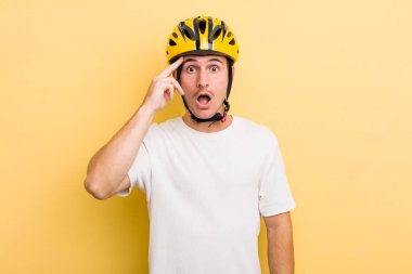 Genç yakışıklı adam şaşırmış görünüyor, yeni bir düşünce, fikir ya da konsept fark ediyor. Bisiklet konsepti motor konsepti