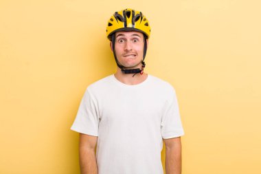 Genç ve yakışıklı adam kafası karışmış ve şaşkın görünüyor. Bisiklet konsepti motor konsepti