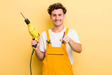 Genç ve yakışıklı bir adam kamerayı işaret ederek seni seçiyor. Matkap konsepti olan bir tamirci.