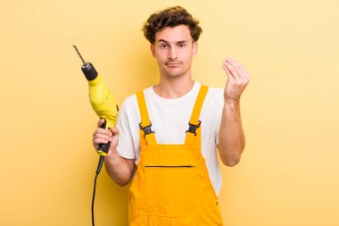 Genç yakışıklı adam kapiş ya da para hareketi yapıyor, sana ödemeni söylüyor. Matkap konsepti olan bir tamirci.