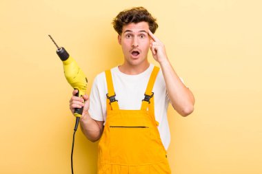 Genç yakışıklı adam şaşırmış görünüyor, yeni bir düşünce, fikir ya da konsept fark ediyor. Matkap konsepti olan bir tamirci.