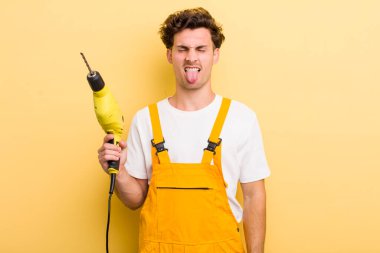 Genç yakışıklı adam iğreniyor, sinirleniyor ve dilini çıkarıyor. Matkap konsepti olan bir tamirci.