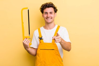 Genç ve yakışıklı bir adam kamerayı işaret ederek seni seçiyor. Tamirci ve testere konsepti