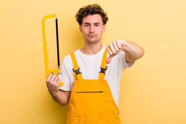 Genç ve yakışıklı adam kendini kötü hissediyor, baş parmağını kaldırıyor. Tamirci ve testere konsepti