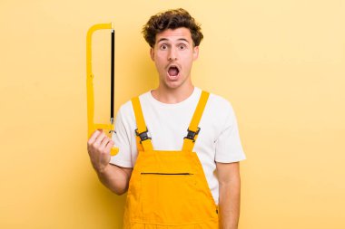 Genç ve yakışıklı adam çok şaşırmış ya da şaşkın görünüyor. Tamirci ve testere konsepti