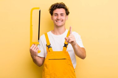 Genç yakışıklı adam gururla gülümsüyor ve kendinden emin bir numara oluyor. Tamirci ve testere konsepti