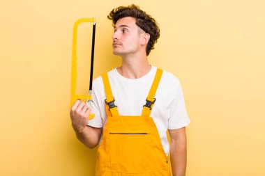 Profil görünümlü genç adam hayal mi kuruyor yoksa hayal mi kuruyor? Tamirci ve testere konsepti