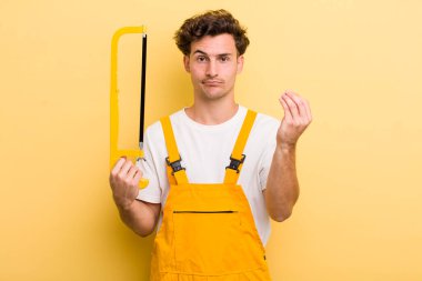 Genç yakışıklı adam kapiş ya da para hareketi yapıyor, sana ödemeni söylüyor. Tamirci ve testere konsepti