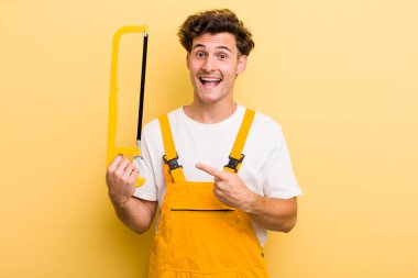 Genç yakışıklı adam heyecanlı ve şaşırmış görünüyor. Tamirci ve testere konsepti