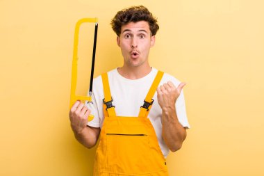 Genç ve yakışıklı bir adam inançsızlığa şaşırmış görünüyor. Tamirci ve testere konsepti