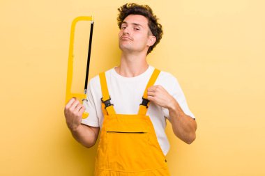 Genç yakışıklı adam kibirli, başarılı, pozitif ve gururlu görünüyor. Tamirci ve testere konsepti