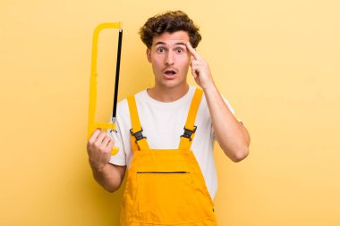 Genç yakışıklı adam şaşırmış görünüyor, yeni bir düşünce, fikir ya da konsept fark ediyor. Tamirci ve testere konsepti