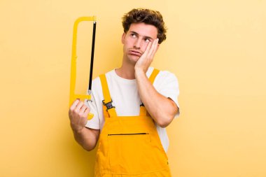 Genç ve yakışıklı bir adam bıkkın, yorgun ve uykulu hissediyor. Tamirci ve testere konsepti