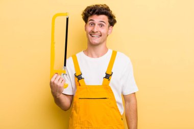 Genç yakışıklı adam mutlu ve hoş bir şekilde şaşırmış görünüyor. Tamirci ve testere konsepti