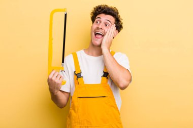 Genç yakışıklı adam mutlu, heyecanlı ve şaşırmış hissediyor. Tamirci ve testere konsepti