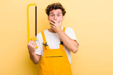 Genç ve yakışıklı adam elleri ile ağzını kapatıyor ve şoka giriyor. Tamirci ve testere konsepti