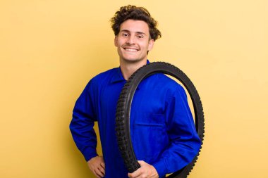 Genç yakışıklı adam mutlu bir şekilde gülümsüyor, eli kalçasında ve kendinden emin. motor mekaniği kavramı