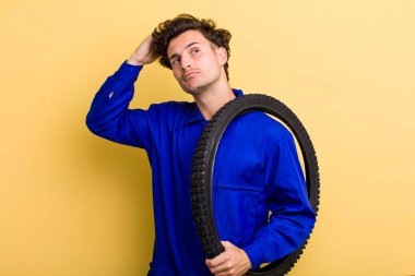 Genç yakışıklı adam mutlu bir şekilde gülümsüyor ve hayal kuruyor ya da şüphe ediyor. motor mekaniği kavramı