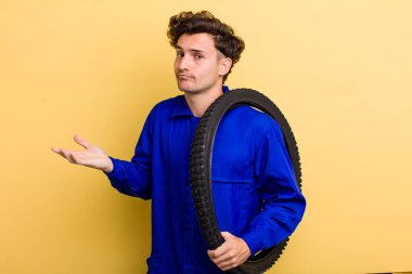 Genç yakışıklı adam şaşkın, şaşkın ve şüpheci hissediyor. motor mekaniği kavramı