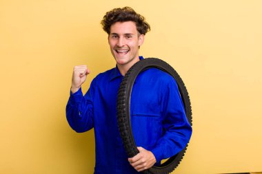 Genç yakışıklı adam şok olmuş hissediyor, gülüyor ve başarıyı kutluyor. motor mekaniği kavramı