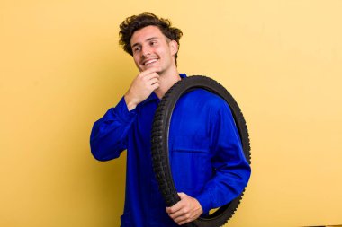 Genç, yakışıklı, mutlu, kendine güvenen ve elleri çenesinde gülümseyen adam. motor mekaniği kavramı