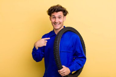 Genç yakışıklı adam kendini mutlu hissediyor ve heyecanla kendini işaret ediyor. motor mekaniği kavramı