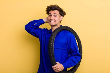 Genç ve yakışıklı adam stresli, endişeli ya da korkmuş, elleri başının üstünde. motor mekaniği kavramı