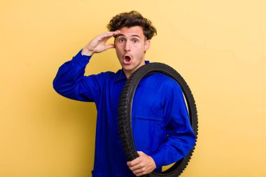 Genç yakışıklı adam mutlu, şaşkın ve şaşırmış görünüyor. motor mekaniği kavramı