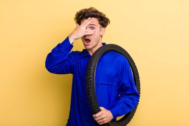 Genç, yakışıklı adam şok olmuş, korkmuş ya da korkmuş görünüyor, yüzünü eliyle kapatıyor. motor mekaniği kavramı